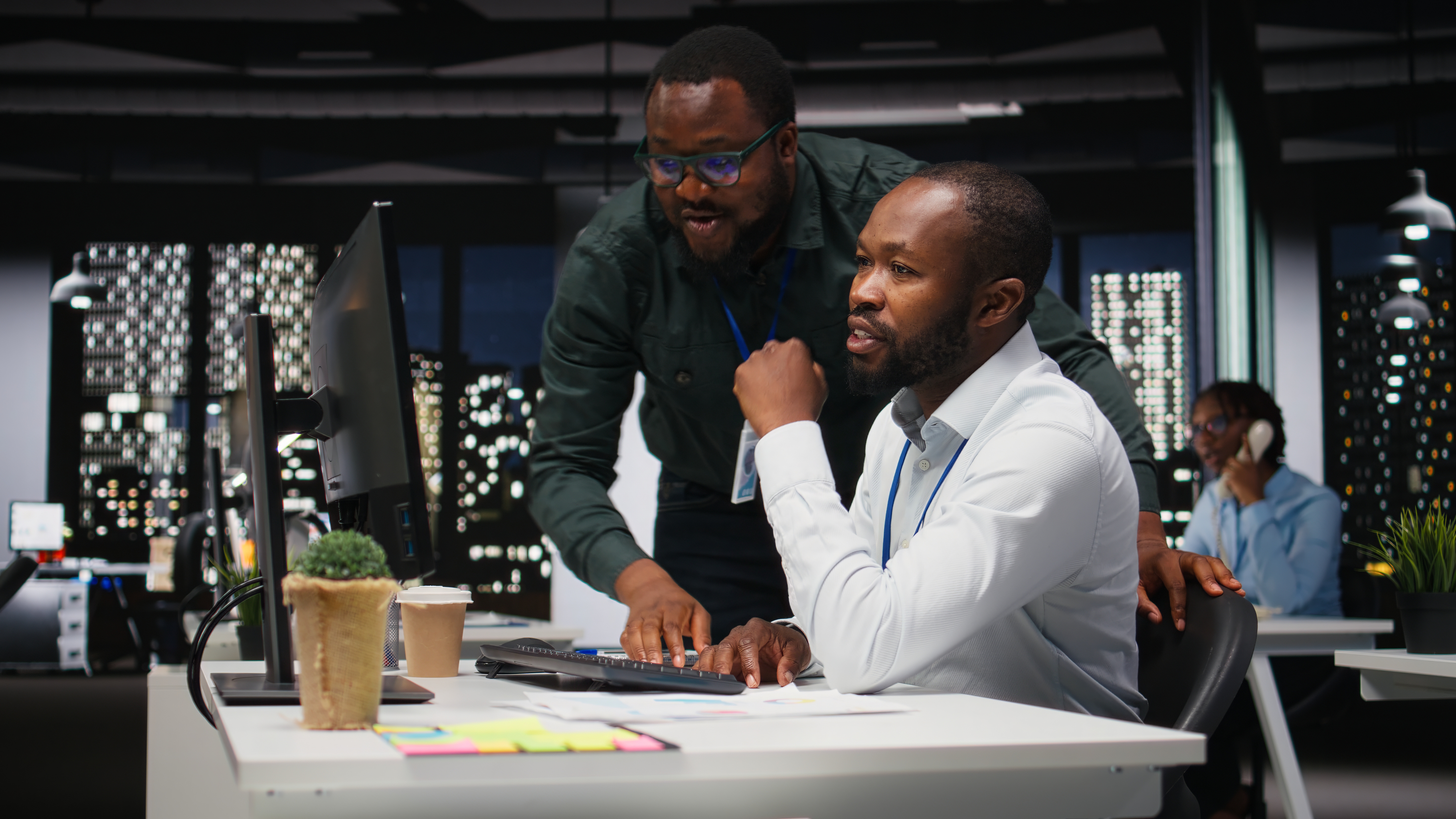 African american staff members consulting each other for monthly reports, reviewing KPI data insights for business productivity late at night. Collaboration between employees for success.